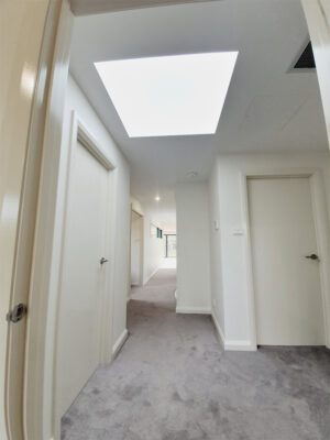 Brightly lit apartment hallway with modern skylight shaft.