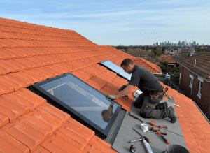 man installing skylight on tiled roof