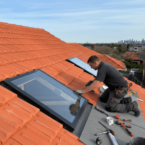 man installing skylight on tiled roof