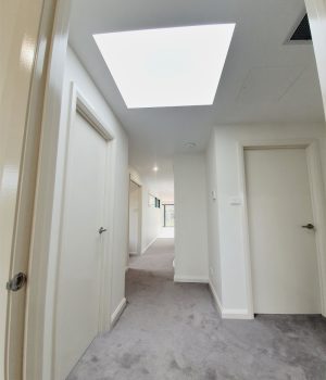 Brightly lit apartment hallway with modern skylight shaft.
